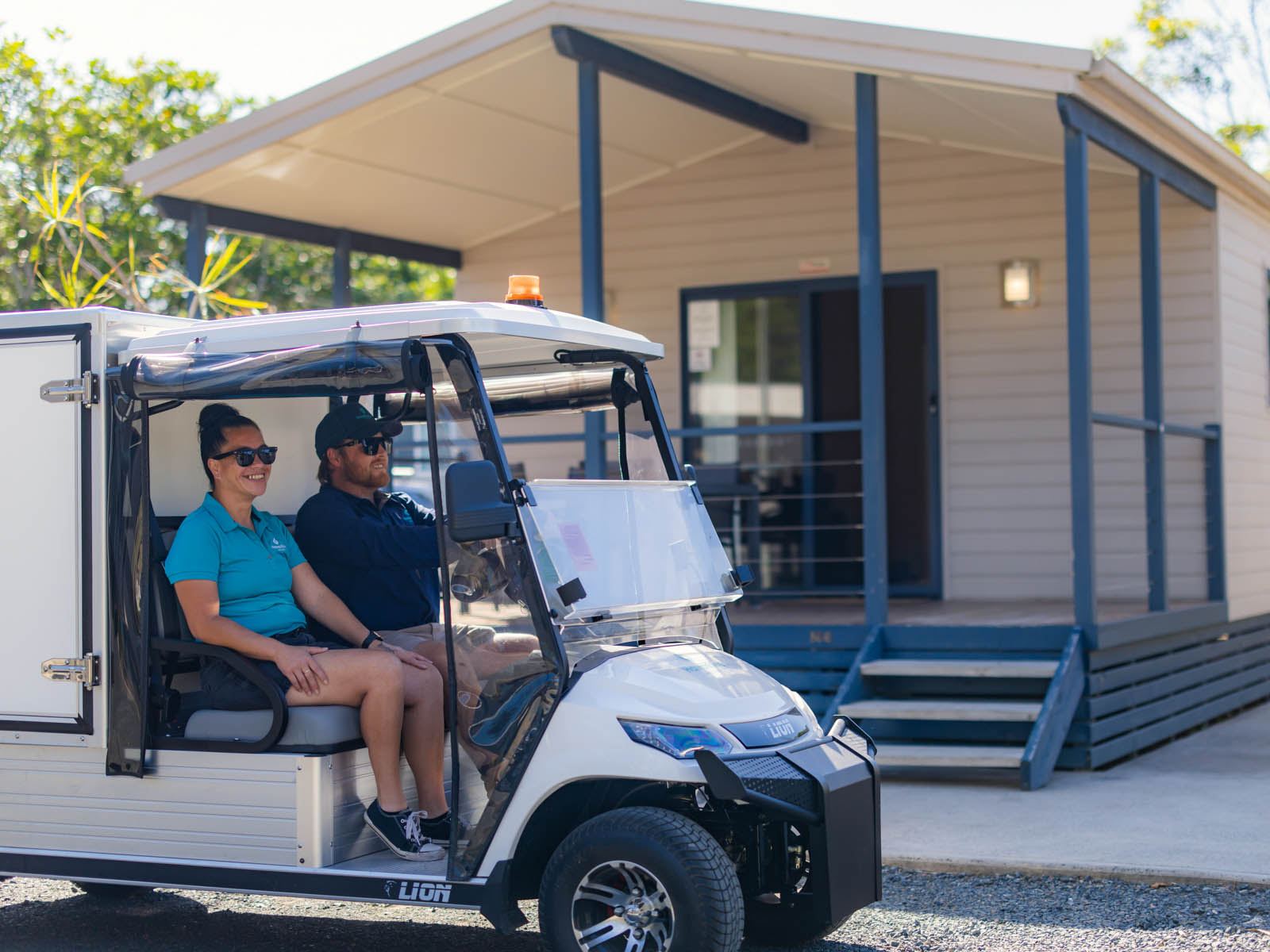 A Hampshire team member driving a golf buggy past cabins